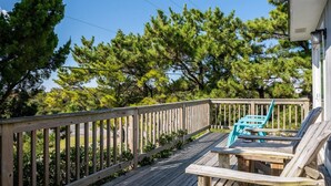 A wooden deck with a railing, a turquoise chair, and a table.