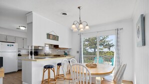 A modern kitchen with white cabinets, a central island, and bar stools.