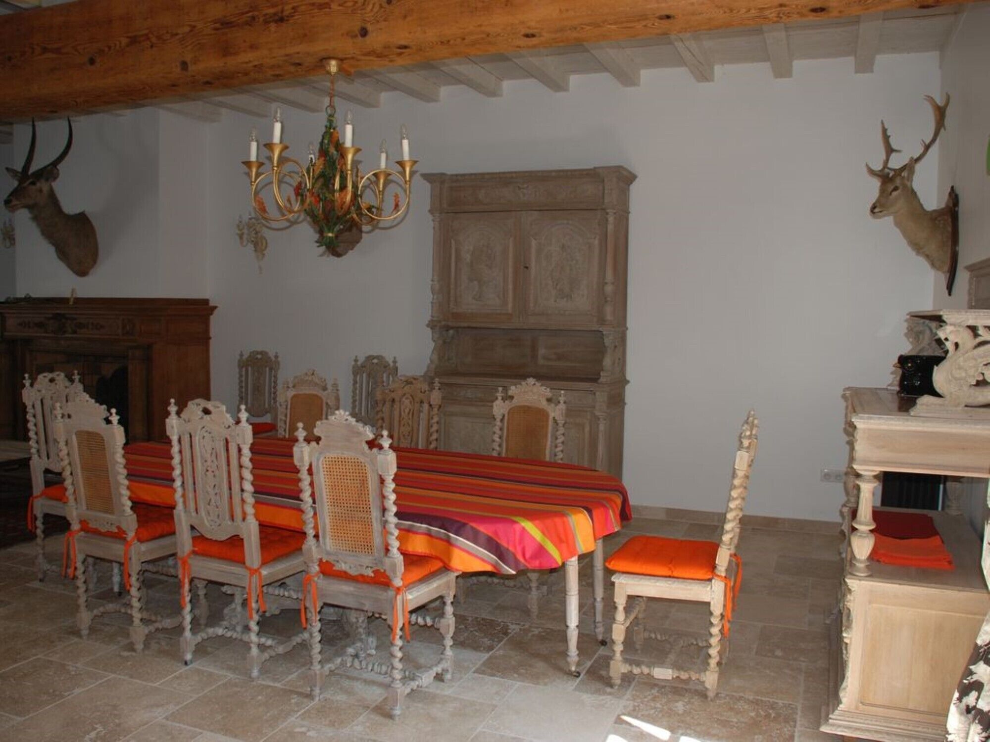 Ein Esszimmer mit einem Holztisch, verzierten Stühlen und einer Kristallleuchter.