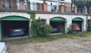 Un edificio con tres puertas de garaje, cada una con un vehículo estacionado adentro.