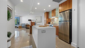 A modern kitchen with a central island, stainless steel appliances, and wooden cabinets. - Cotton Beach 35 with Pool Views - Beachfront Complex (Casuarina)