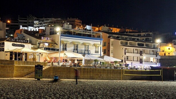 A beachfront area with a restaurant named 'El Barquito' and a building with a blue facade.
