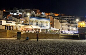 Ein Strandabschnitt mit einem Restaurant namens 'El Barquito' und einem Gebäude mit blauer Fassade.