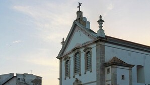 A historic building with a white facade, a bell tower, and a weather vane.