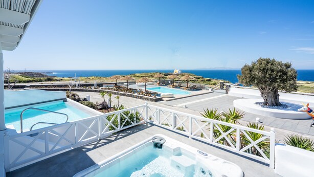 Un área de piscina en la azotea con varias piscinas, un jacuzzi y vistas al océano.