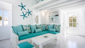 Una sala moderna con un sofá color turquesa, una mesa de centro blanca y decoración de pared con forma de estrella de mar.
