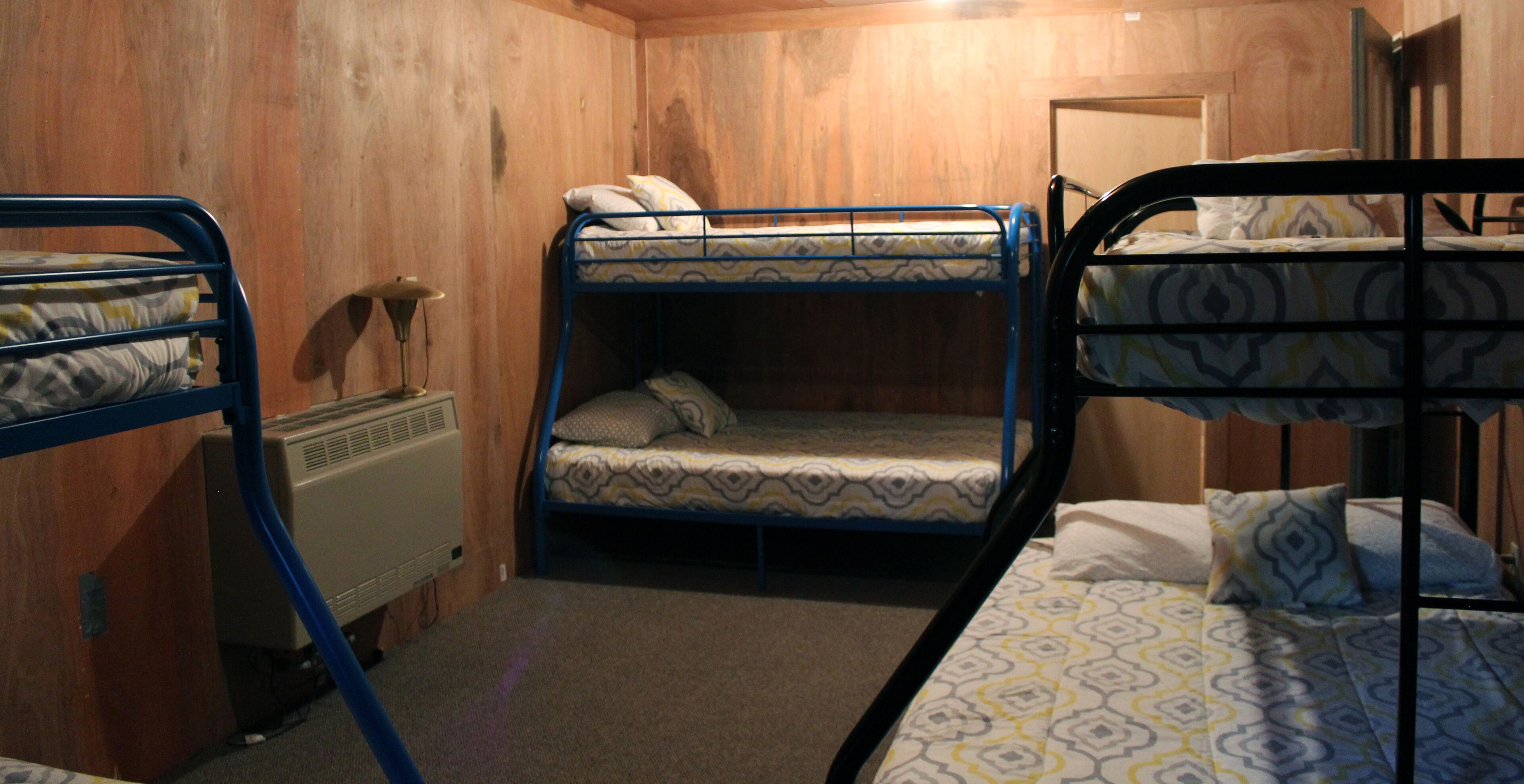 A room with bunk beds, a heater, and wooden walls.
