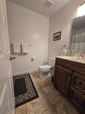 Een bad/douchecombinatie, een haardroger, handdoeken, zeep