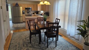 Eine moderne Küche mit Holzschränken, einer eingebauten Kochinsel und einem Essbereich mit Tisch und Stühlen.