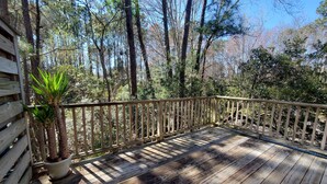 Eine Holzterrasse mit Geländer, umgeben von Bäumen und einem Blumentopf.