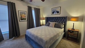 Ein Schlafzimmer mit einem großen Bett, einem Deckenventilator, zwei Nachttischlampen und einem gerahmten Bild an der Wand.