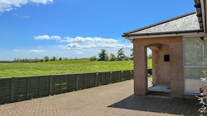 Een gebouw met een gevel van natuursteen, een pannendak en een patio met bakstenen bestrating.
