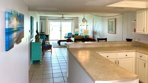 A kitchen with a large island, white cabinets, and a dining area with chairs and a table.