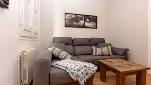 Una sala de estar con un sofá gris, una mesa de centro de madera y un cuadro enmarcado en la pared.