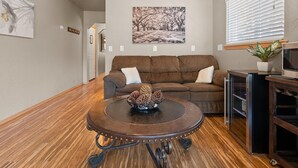 Ein Wohnzimmer mit einem braunen Sofa, einem Couchtisch mit Kiefernkegeln, einem Gemälde und einem Fernsehschrank.