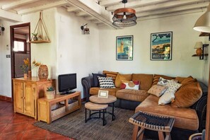 A cozy living room with a wooden cabinet, a television, a sofa, and a small round table.