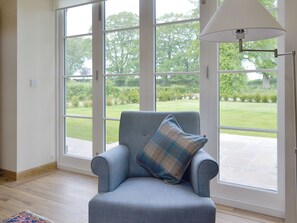 Une pièce avec un fauteuil bleu, un coussin à carreaux et une lampe blanche.