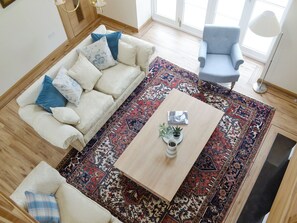 A living room with a sofa, armchair, coffee table, and patterned rug. - The Stables - UK11108 (Montrose)