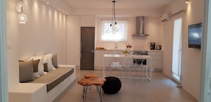 A modern kitchen with a built-in refrigerator, a dining area with a white table and chairs, and a seating area with a sofa and ottoman. - Modern House near Parikia with 3 bedrooms & 2 bath (Πάρος)