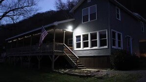 Uma casa de dois andares com varanda, uma bandeira e uma escadaria.