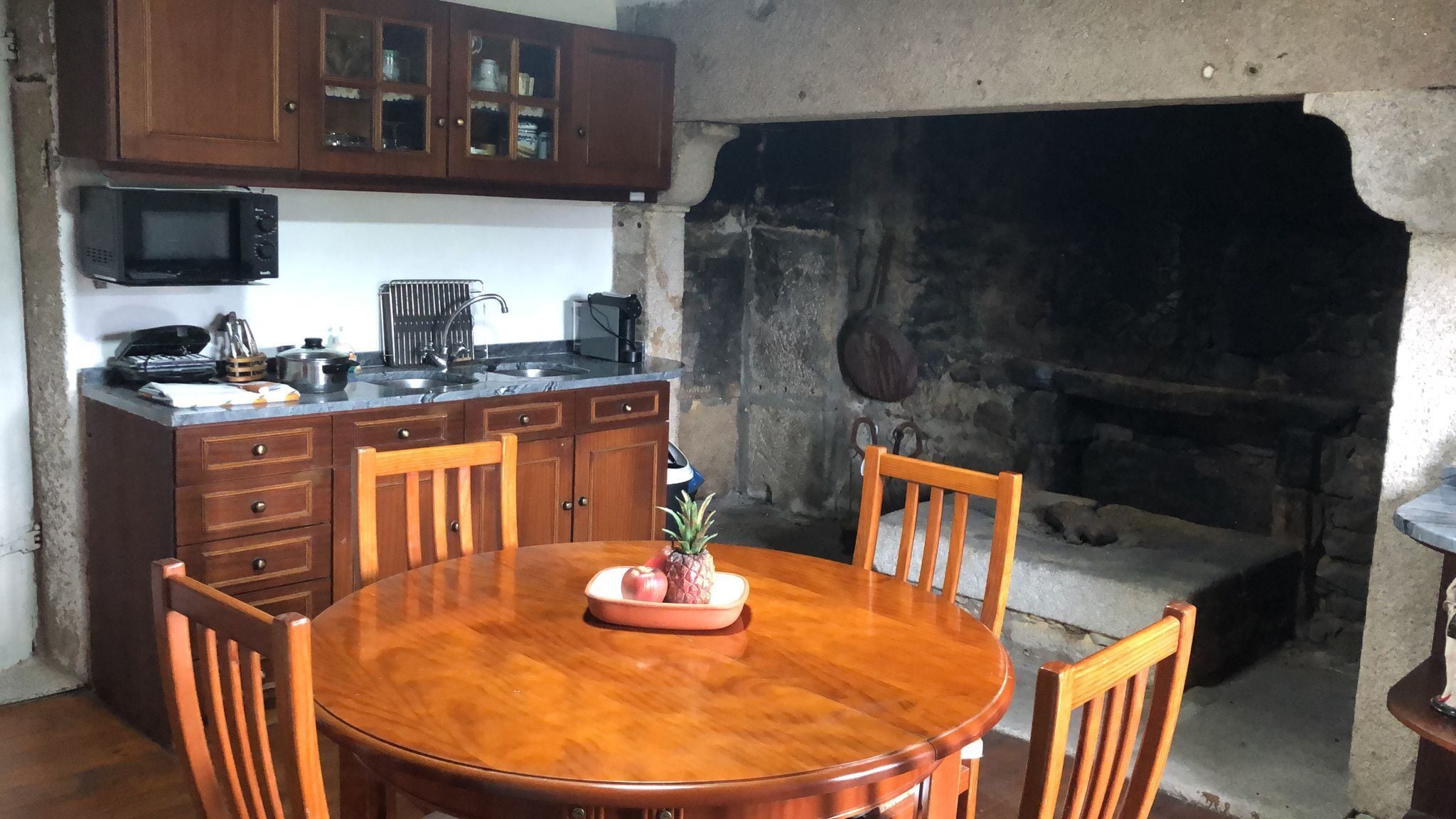 Une cuisine avec des meubles en bois, un four à micro-ondes et une cheminée en pierre.