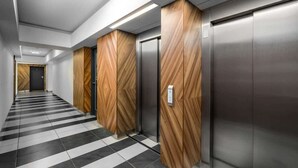 Ein moderner Aufzugsbereich mit Holzvertäfelung und einem Schachbrettmuster-Boden.