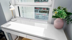 Ein weißer Schreibtisch mit einer Lampe und einem Blumenstrauß.