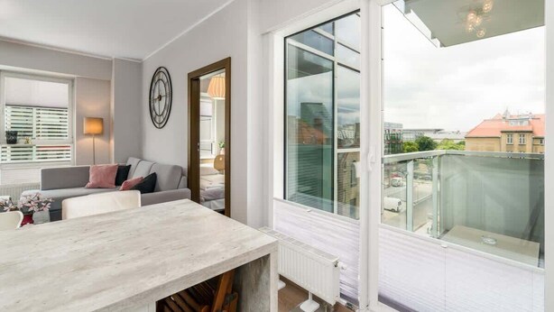 Ein modernes Wohnzimmer mit Essbereich, großen Fenstern und Blick auf die Stadt.