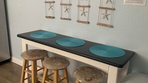 A kitchen with a wooden bar counter, three stools, and a hanging starfish decoration.