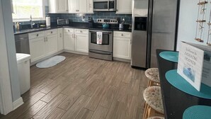 A modern kitchen with white cabinets, stainless steel appliances, and a wooden floor.