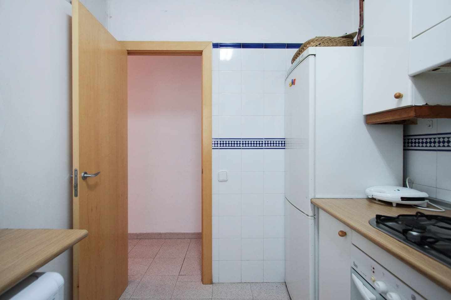 A compact kitchen with a wooden door, white cabinets, a gas stove, and a small countertop.