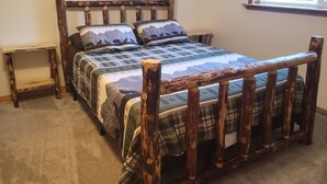 Un lit avec un cadre en bois et une couvre-lit à motifs de montagne.