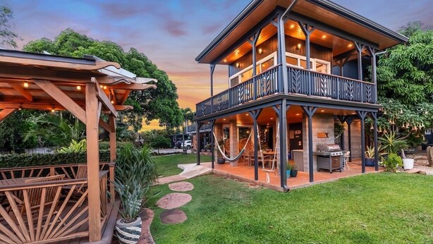 Ein zweistöckiges Haus mit Balkon, Sitzbereich im Freien und einem Grill.