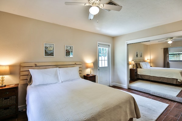 A bedroom with a bed, bedside lamps, a ceiling fan, and a large mirror. - Lovely cottage close to beach (Nokomis)
