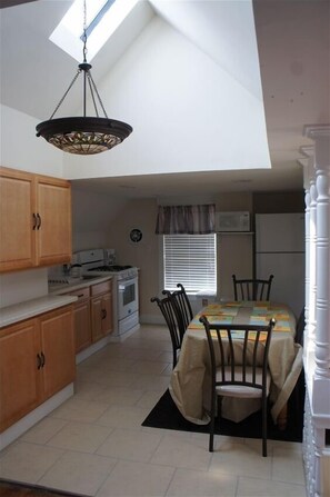 Enjoy cooking in this kitchen with a skylight, microwave, stove, and dining table.