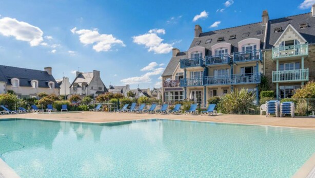 A swimming pool with lounge chairs and a row of houses in the background. - L'Eclose - Cap Marine, gîte in Guilvinec (Guilvinec)