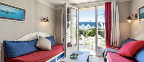 Una habitación con dos camas, una mesa y vistas al exterior.