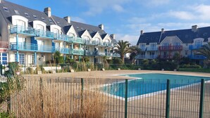 A hotel with multiple balconies, a swimming pool, and a well-maintained garden area. - L'Eclose - Cap Marine, gîte in Guilvinec (Guilvinec)