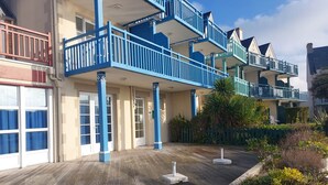 A multi-story hotel with blue balconies, a wooden deck, and a garden area. - L'Eclose - Cap Marine, gîte in Guilvinec (Guilvinec)