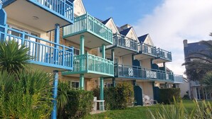 A row of multi-story buildings with balconies, surrounded by greenery and palm trees. - L'Eclose - Cap Marine, gîte in Guilvinec (Guilvinec)