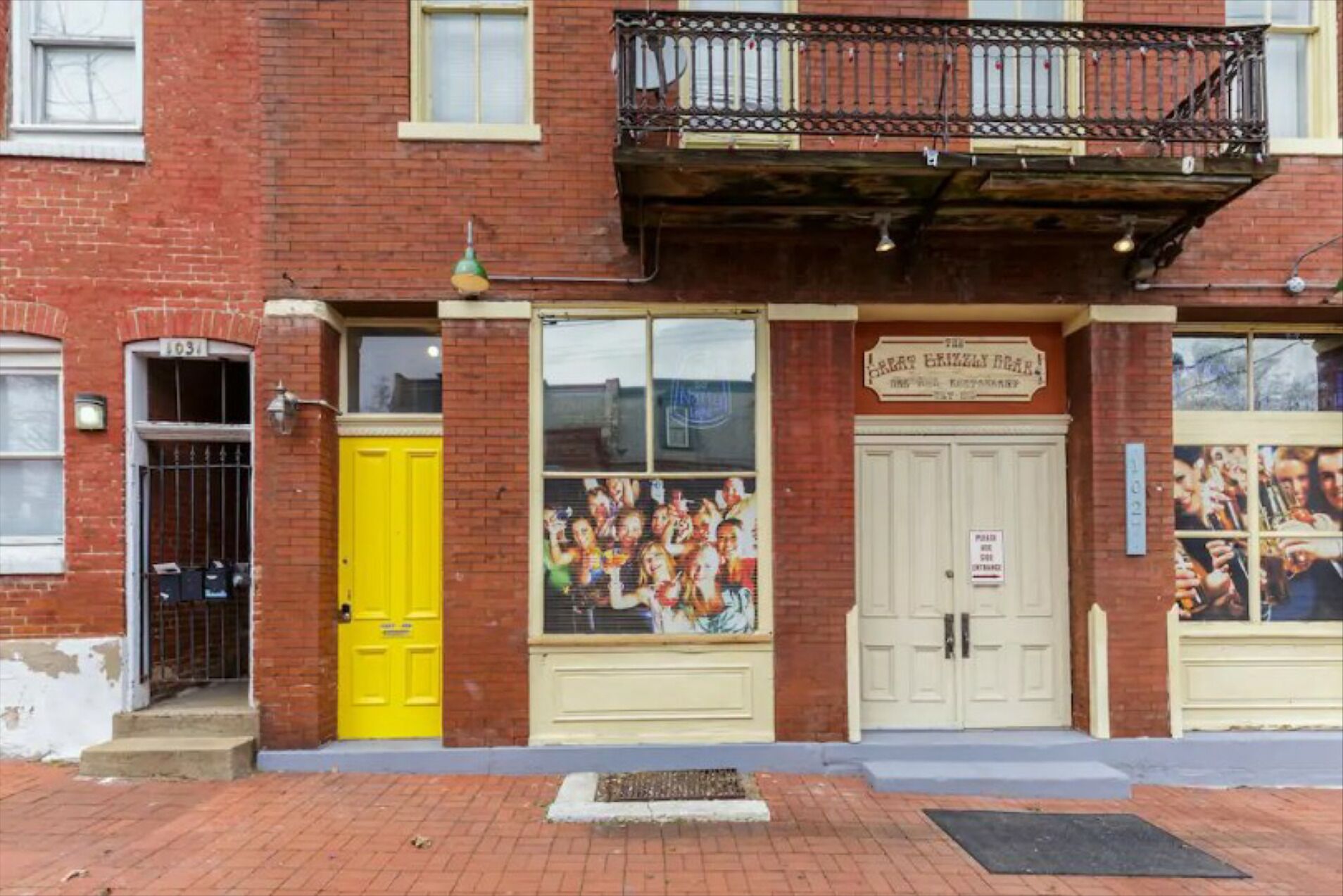 A building with a yellow door, a sign reading "The Grizzly Bear Restaurant," and a large window with a mural.