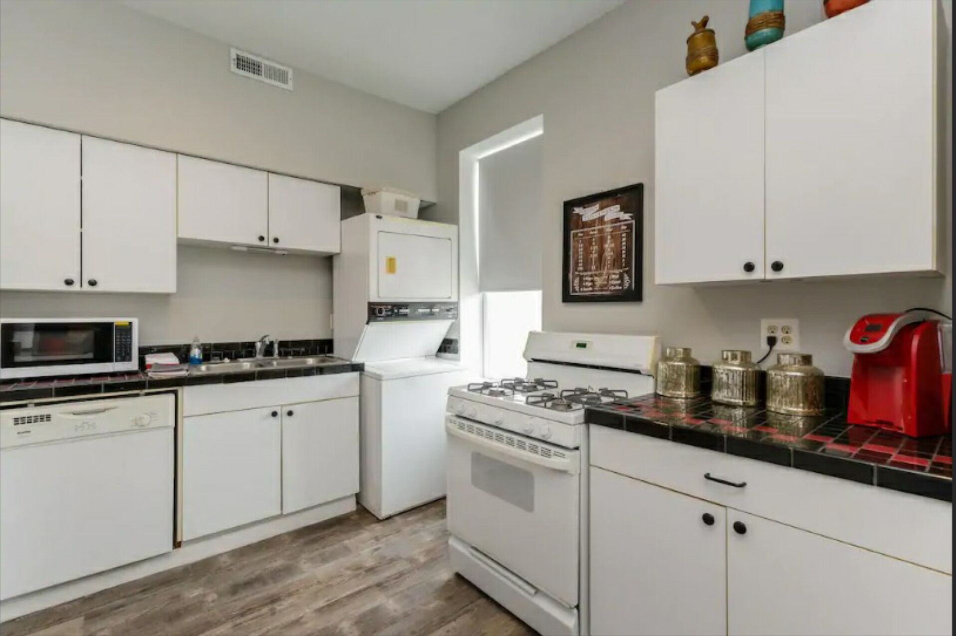 A kitchen with white cabinets, a microwave, a gas stove, and a coffee maker.