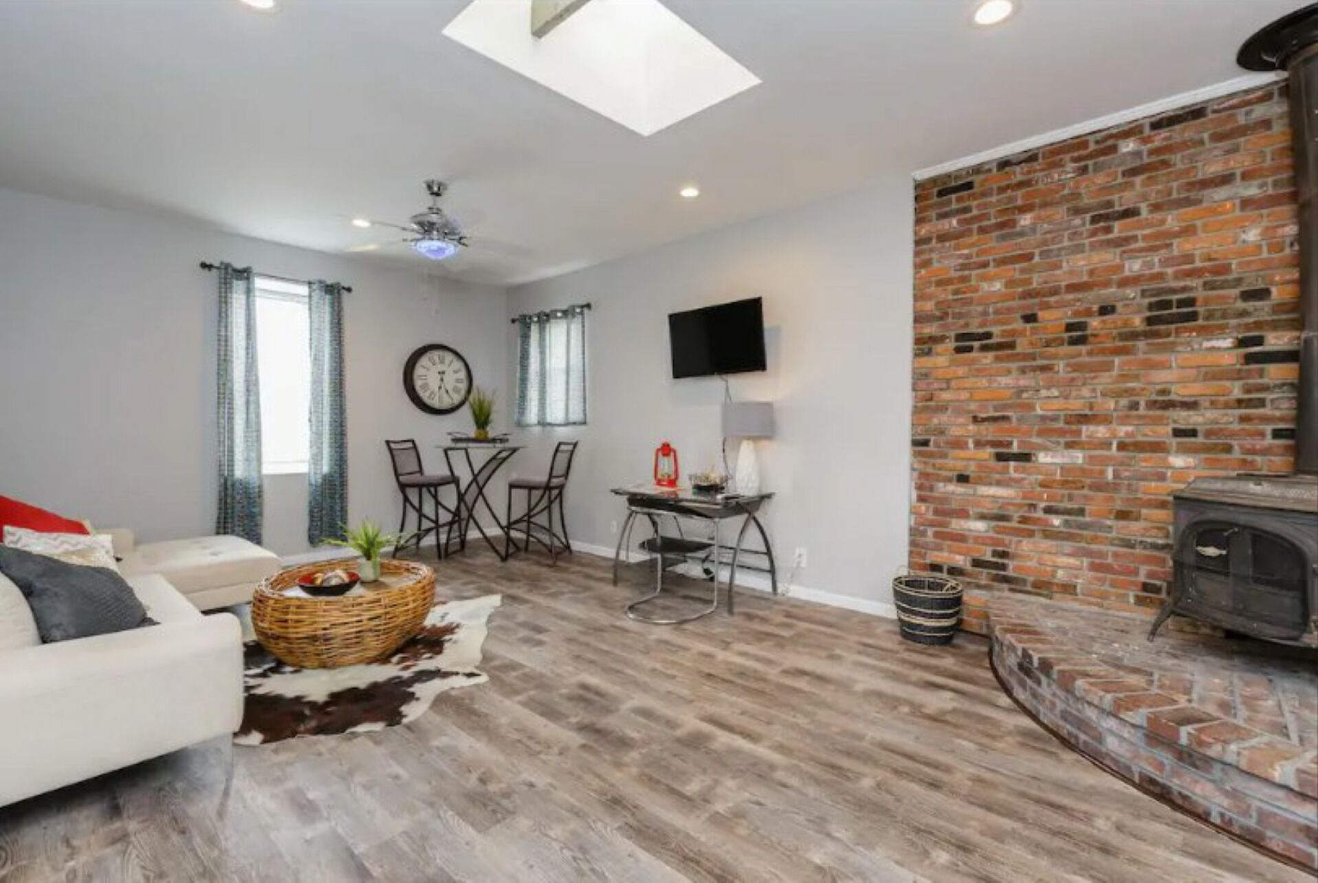 Un salon moderne avec une cheminée, un coin repas avec une table et des chaises, et un espace salon confortable avec un canapé et un panier décoratif.