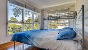 A bunk bed room with a view of trees through large windows. - Raywood - sleeps up to 17 (COWES)