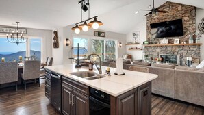 A modern kitchen with a stone accent wall, a built-in island, and a large TV above the fireplace. - High Heaven Mountain top dream (Sapphire)