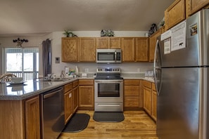 Enjoy cooking in this kitchen with a window offering a view of the outdoors, featuring a dishwasher, oven, and refrigerator.