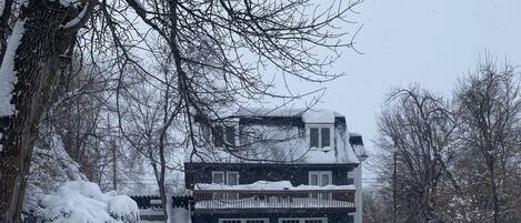 Ein zweistöckiges Haus mit Garage, umgeben von schneebedeckten Bäumen.
