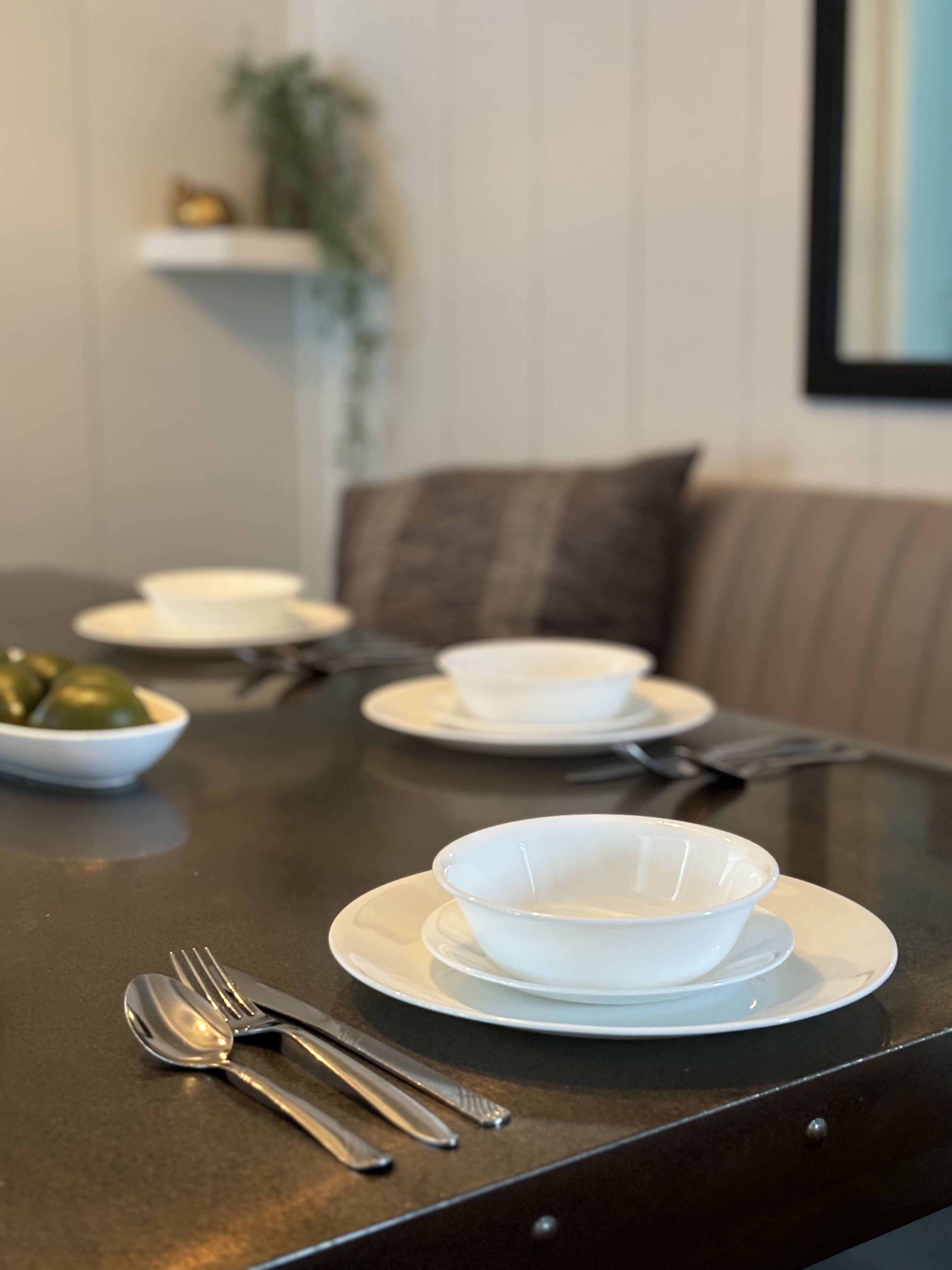 A dining table set with white bowls, plates, and cutlery.