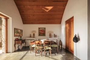 A dining area with a wooden table and chairs, a vase with flowers, and a painting on the wall.