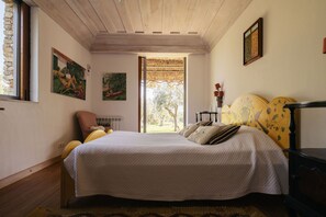 A bedroom with a large bed, a window, and artwork on the walls.